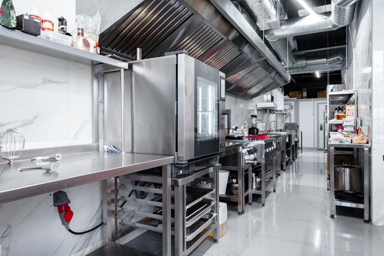 A clean and modern commercial kitchen with stainless steel appliances, a commercial induction cooker, and marble walls.