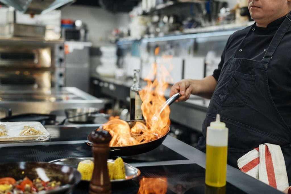 Chef cooking with a flaming pan on a Commercial Induction Cooker in a commercial kitchen.